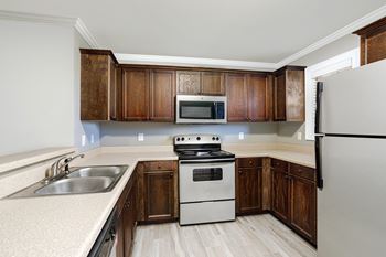 Kitchen with a refrigerator, microwave, stove, and brown wooden cabinets